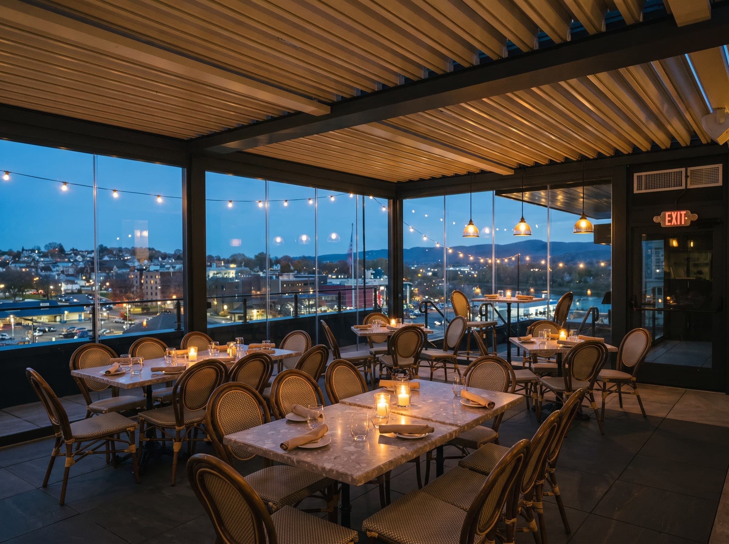 Restaurant sur toit-terrasse au crépuscule sous une pergola à lames, parois vitrées, tables aux bougies et guirlandes lumineuses