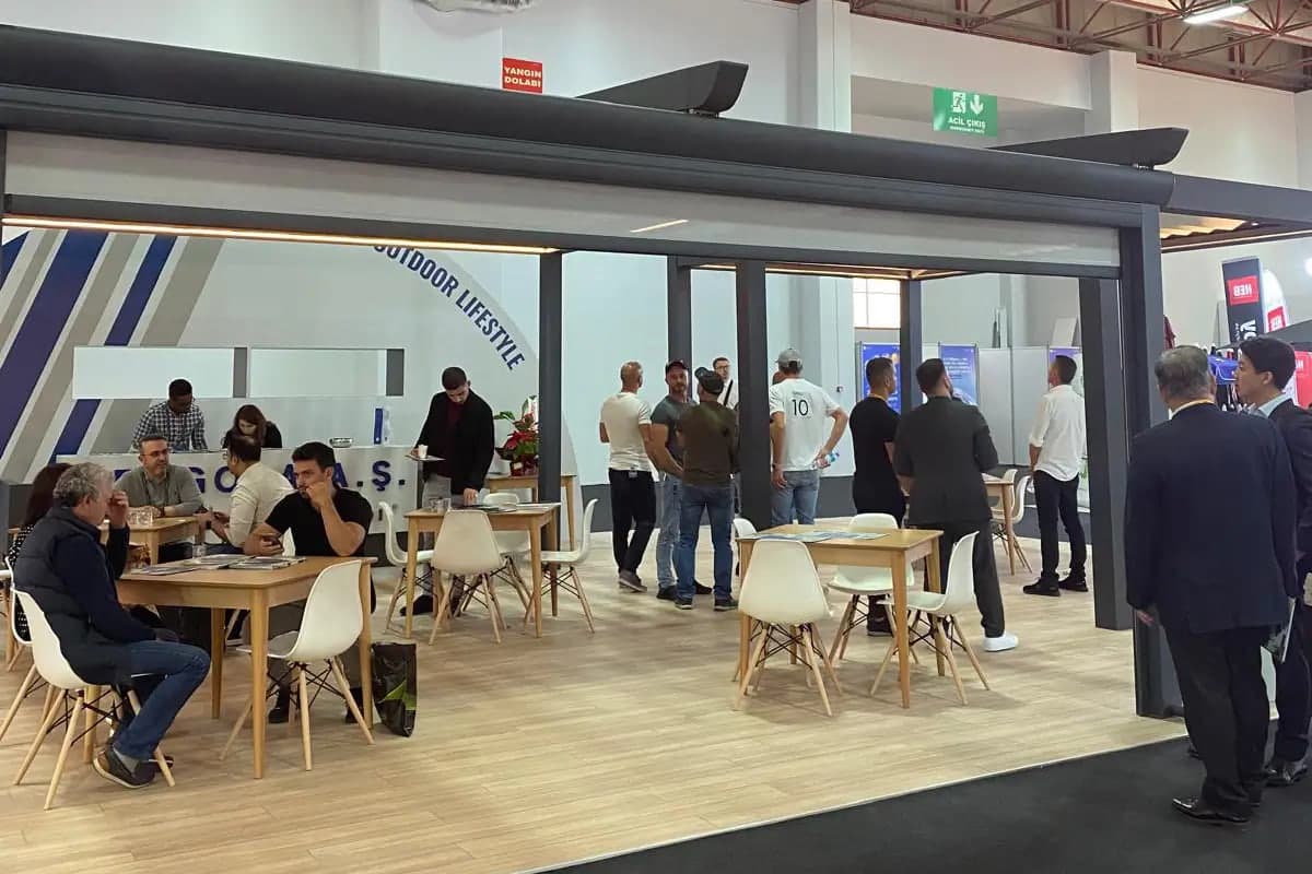 Visitors in conversation at tables on the Pergola Inc. trade fair stand
