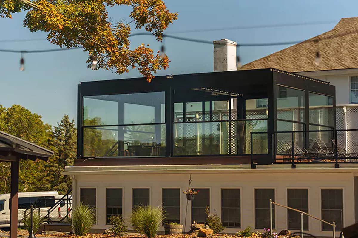 Black-framed glass enclosure pergola on the rooftop terrace of a building