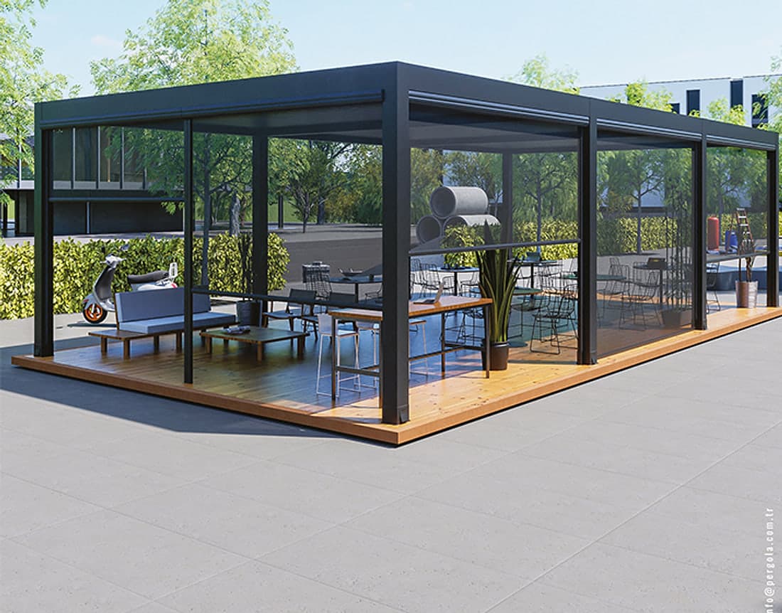 Toldo zip i-Zip Screen: gran pérgola oscura con toldos transparentes bajados en todos sus lados, tarima y muebles de estar