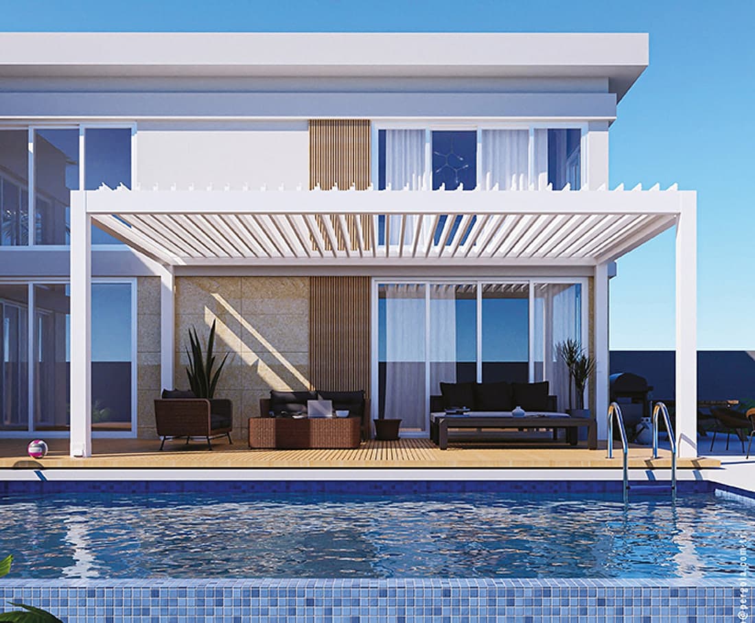 SkyPro bioclimatic pergola with open white louvres in front of a modern white house, timber deck, lounge furniture and pool